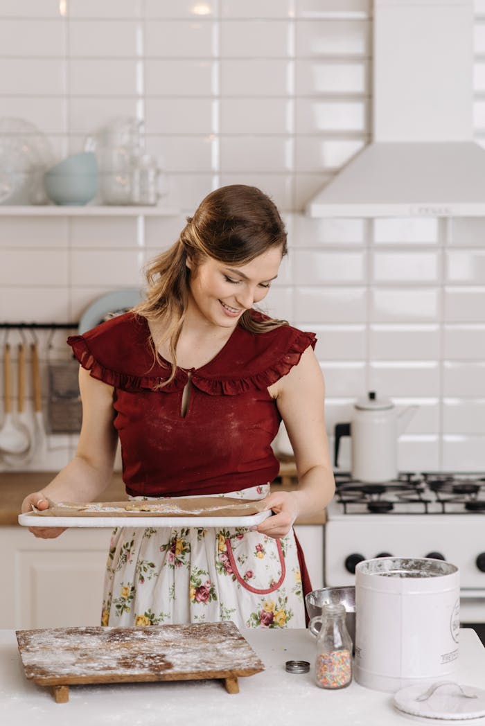 Smiling woman in a kitchen prepares homemade cookies, embracing culinary joy.