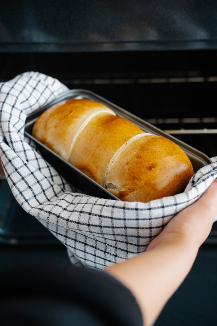 Homemade bread being placed in oven on baking tray by hand. Perfect golden crust.